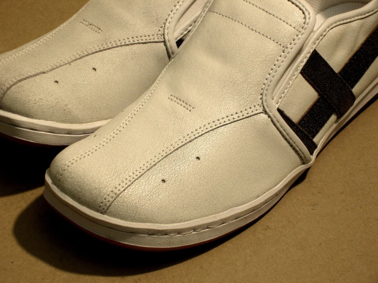 white, leather sneaker with black cross painted on the side
