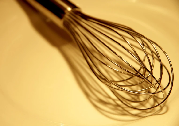 the whisk is sitting in a glass bowl