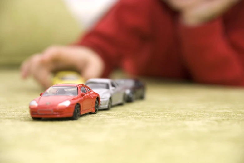 the toy cars are lined up in one direction, and the child looks on