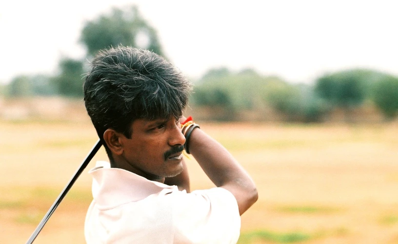 an indian golfer has his golf club in hand and is trying to hit