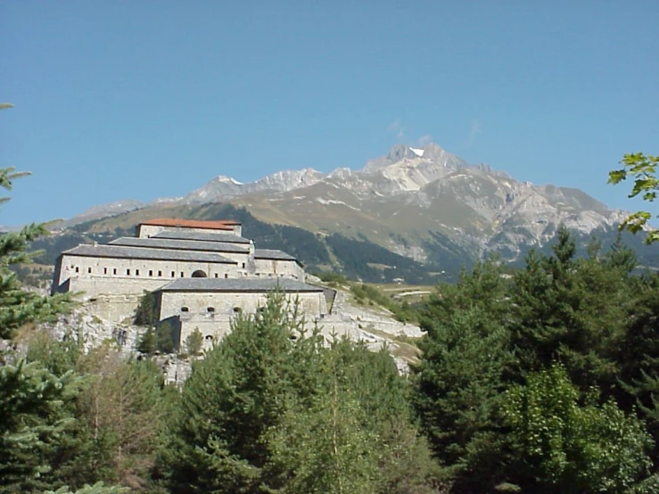 a castle sitting among trees and mountains in the background