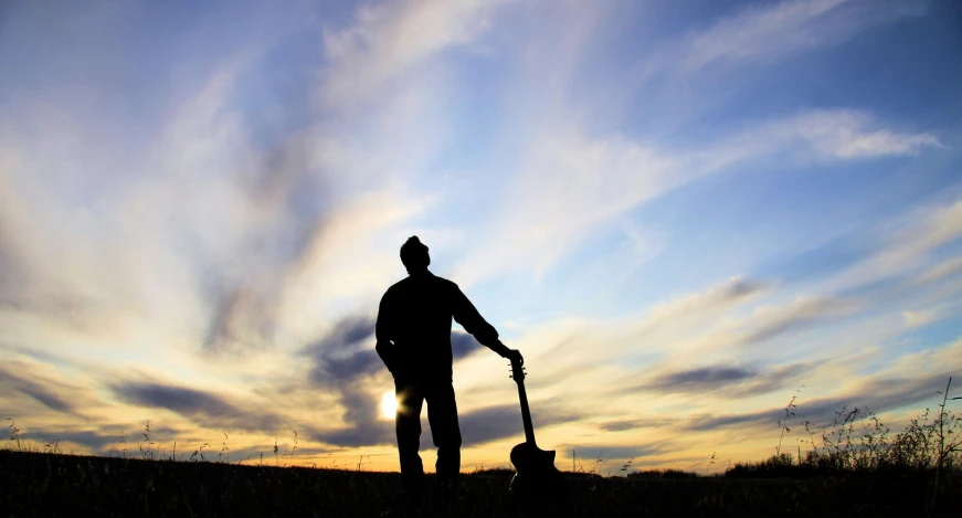 a man holding a shovel standing on top of a field