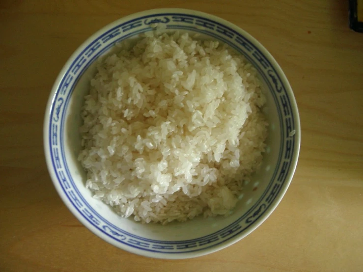 bowl of white rice on wooden surface with wood table