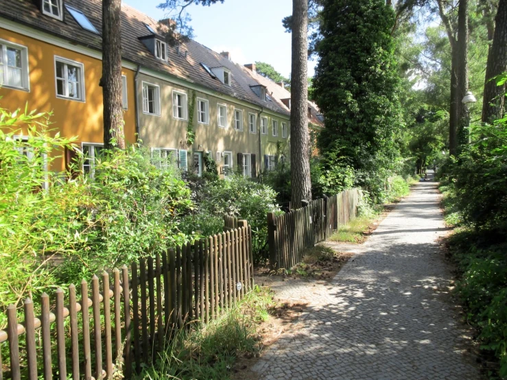 a pathway that runs past two buildings near trees