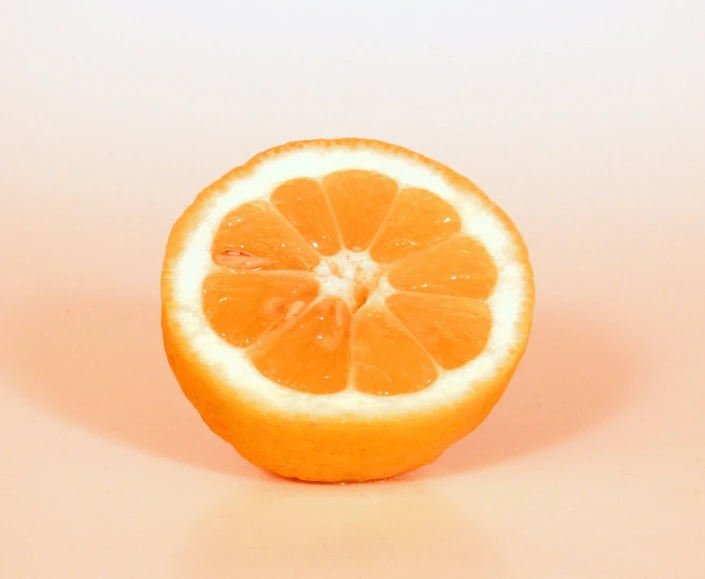 orange slice cut in half on a pink background