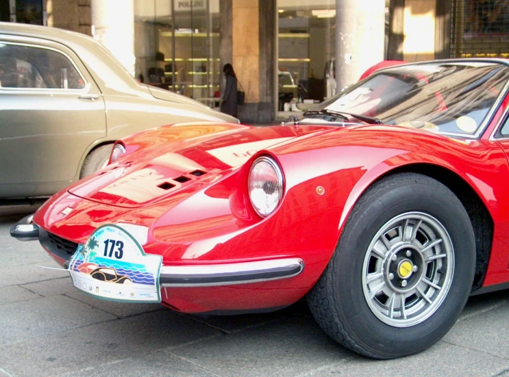 there is a old red sports car parked in the street