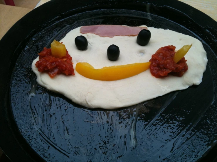 a decorated face made of dough on a black plate