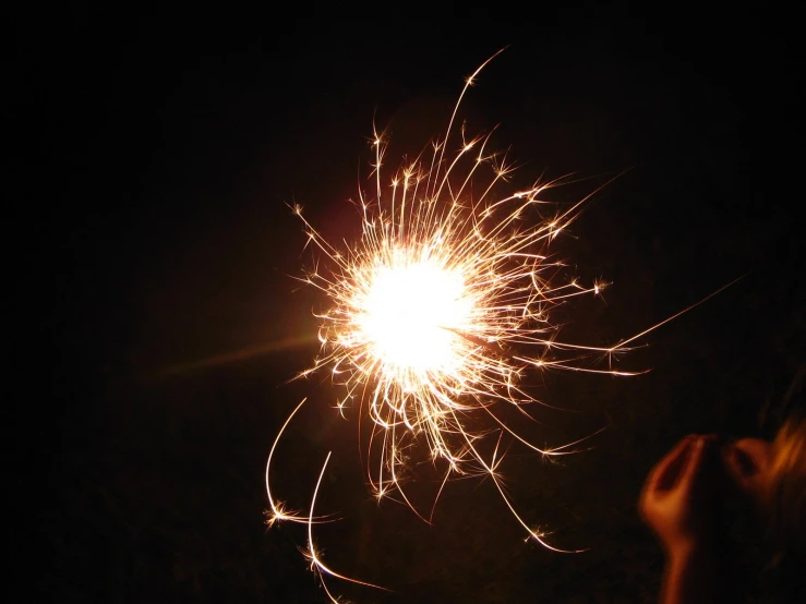 a person holding their hand in front of a fireworks