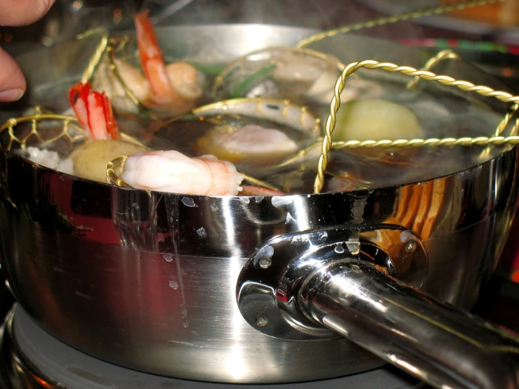 a close up view of an open pot with shrimp and vegetables