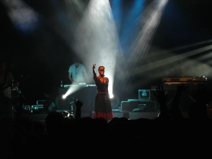 a person on stage with a lit up stage and several people around her