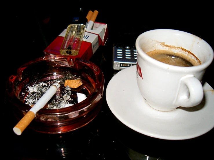 a cup of coffee and cigarette on top of a table