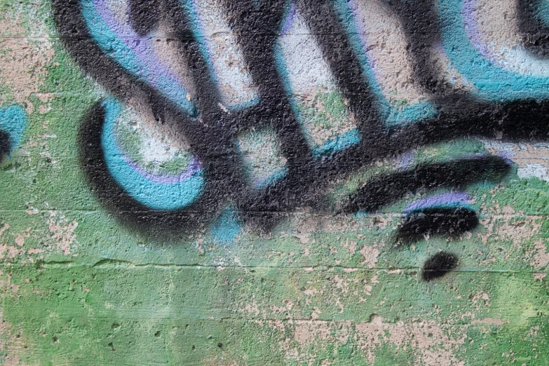 the graffiti is on the wall painted with blue, green and black colors