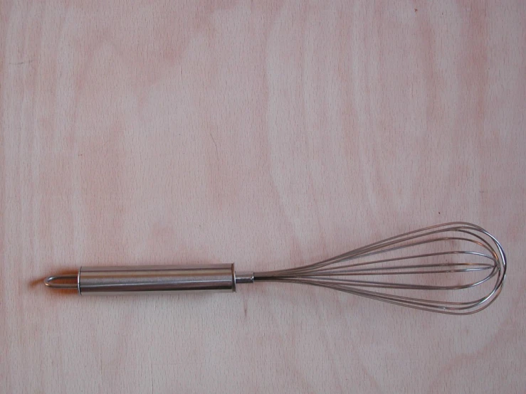 an image of a stainless steel whisk on wooden background
