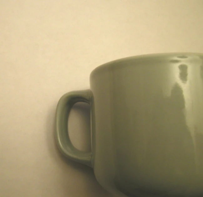 a green coffee mug is sitting on a white surface