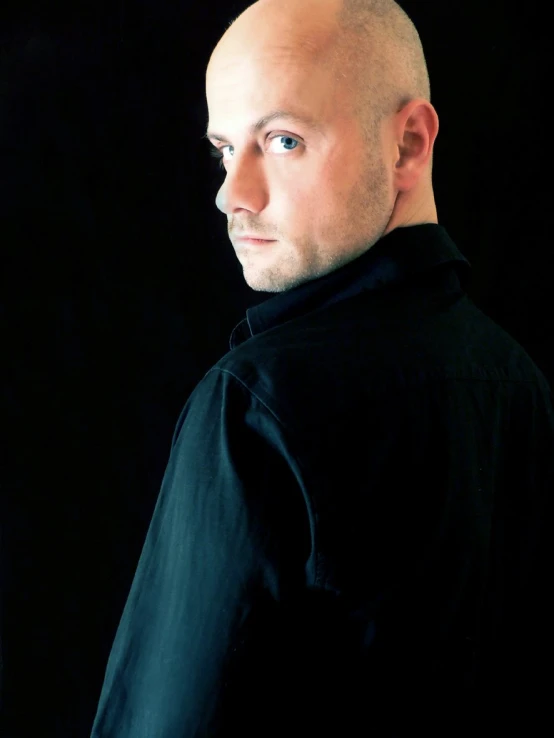 bald man with blue eyes in black outfit