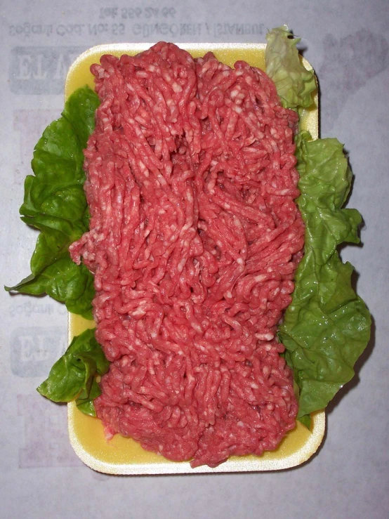 a square plate with greens and ground meat