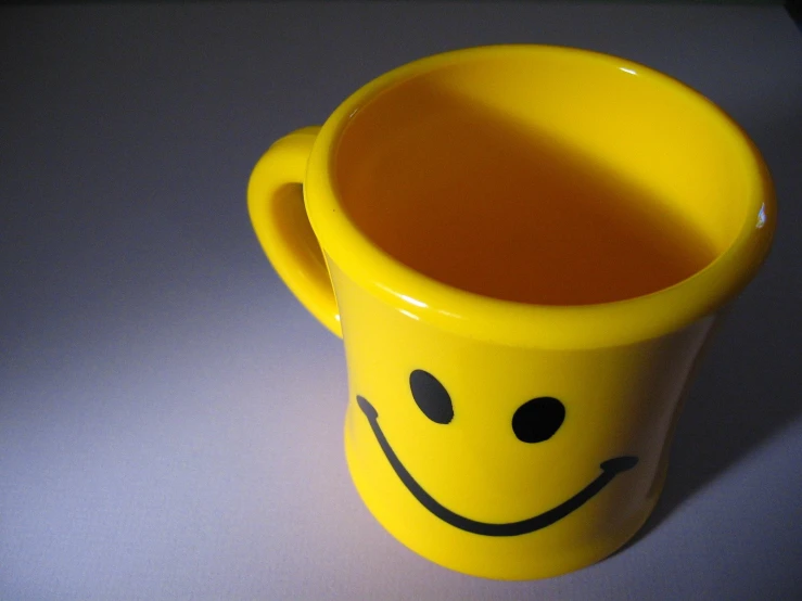 a bright yellow coffee mug with a smiley face drawn on it