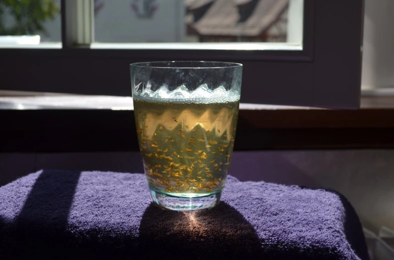 a glass filled with water sitting on top of a blue towel