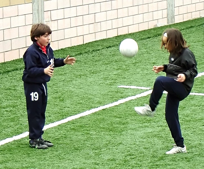 two young people play with a soccer ball
