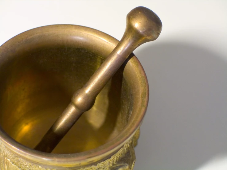 an antique metal cup and spoon with a handle