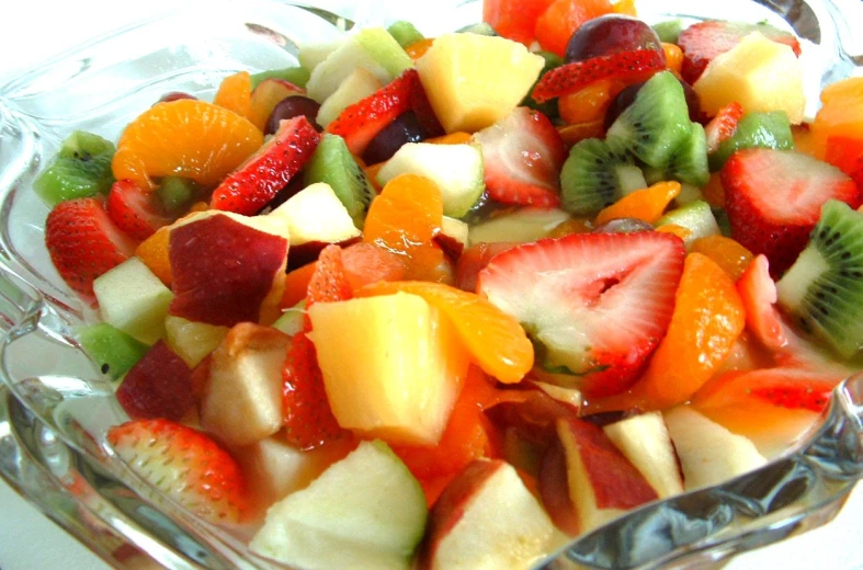 a fruit salad is displayed in a glass dish