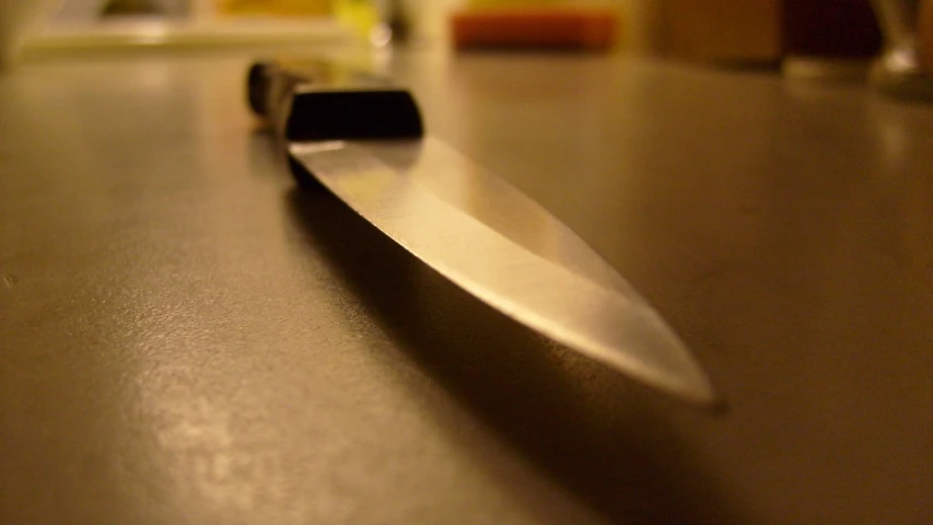 a knife sits on a table with empty wine glasses in the background