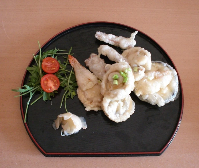 an plate that has dumplings and a tomato on top of it