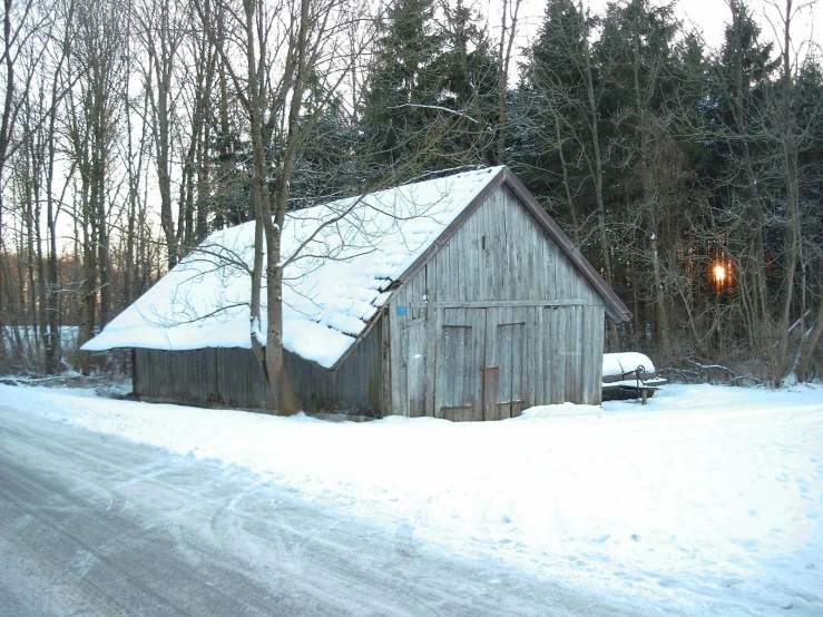 a barn sitting on the side of a road in the winter