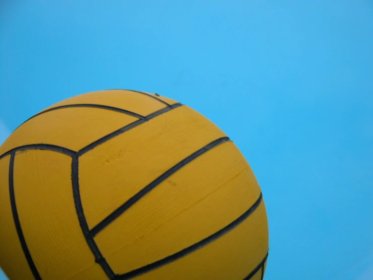 a close up of a yellow volleyball on a sunny day