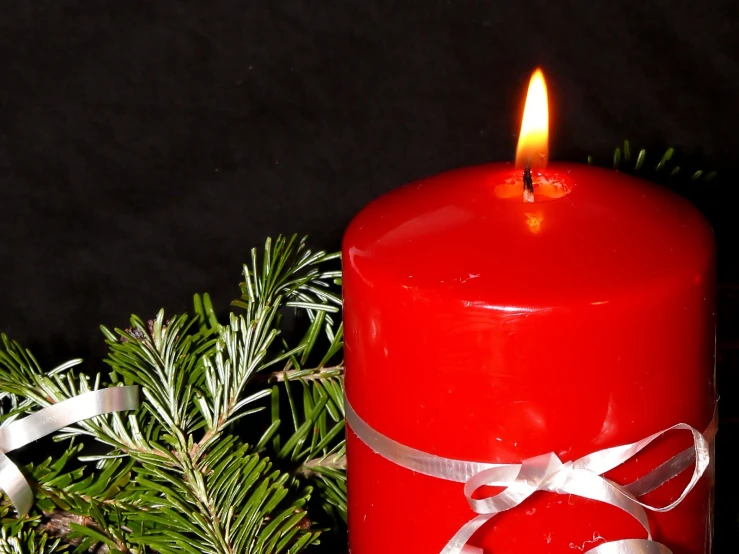 red candle with a white ribbon and pine tree