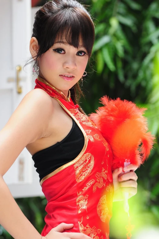 a beautiful young woman holding an orange feather ball