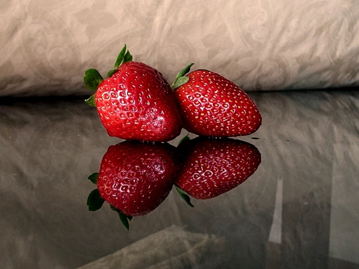 five strawberries stacked on top of each other with green leaves