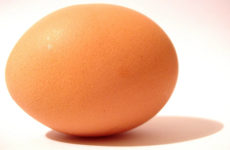 an egg sitting on a white surface in a single image