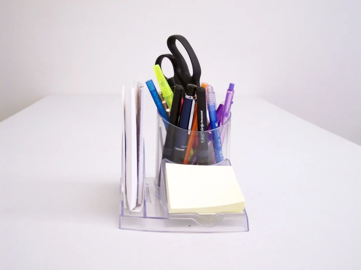a holder with pens, pencils and paper on the table