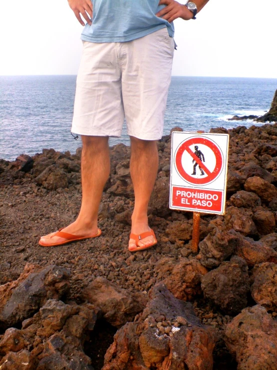 a man stands on a rocky cliff beside the ocean