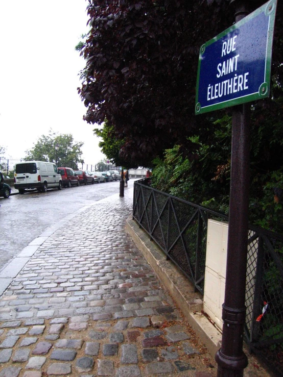 a street sign on the corner of a small brick road