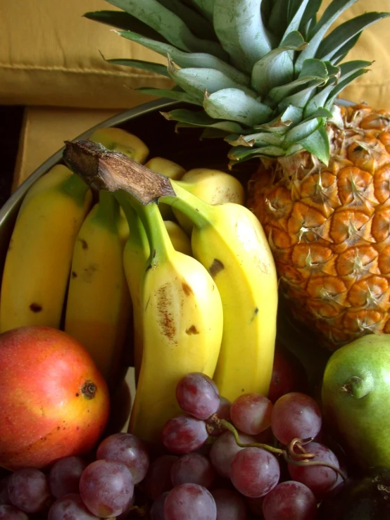 a basket filled with fruit such as bananas, apples, and pineapples