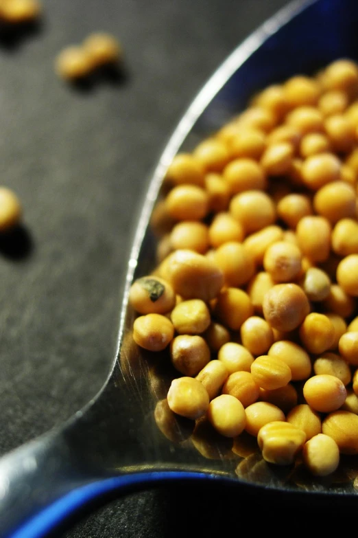 a spoon is filled with chickpeas and sits on a table