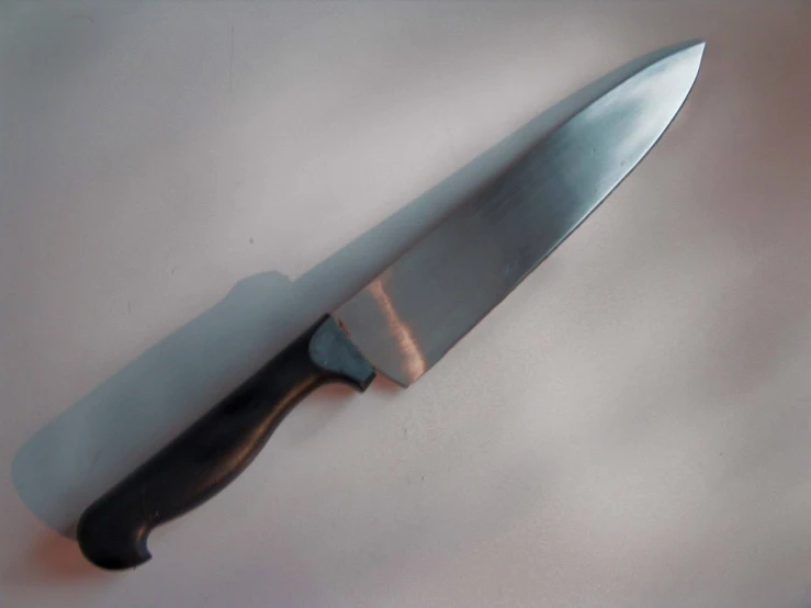 a kitchen knife with a black handle sitting on a counter