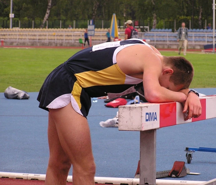 man in running shorts leans his head against the back of his running bench