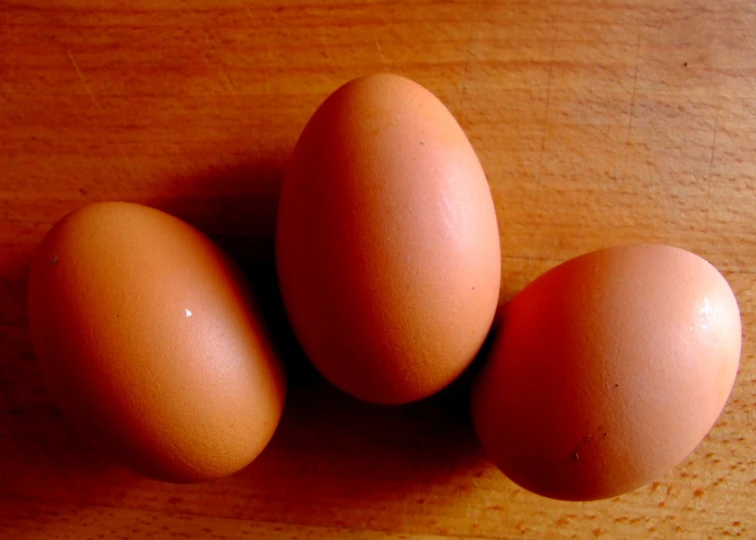 three eggs are shown next to each other on a wooden surface