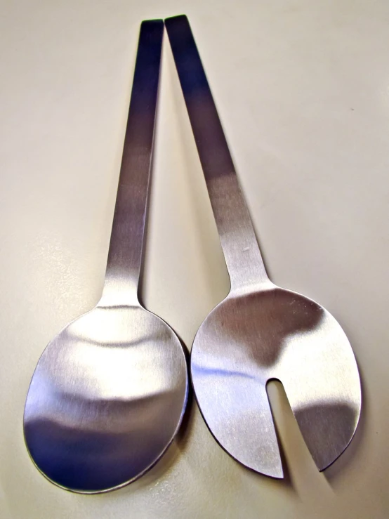 two metal spoons and forks on a table