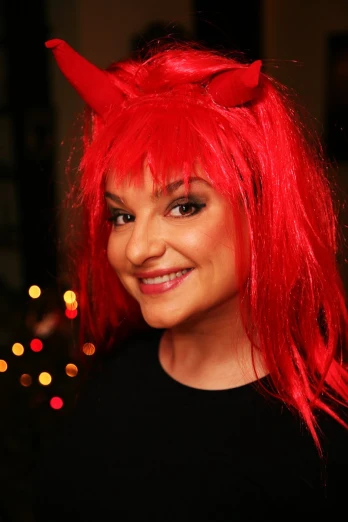 a girl wearing red wigs and horns looks into the camera