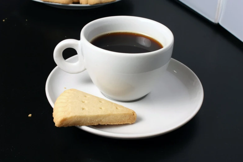 a cup of coffee next to two plates of biscuits