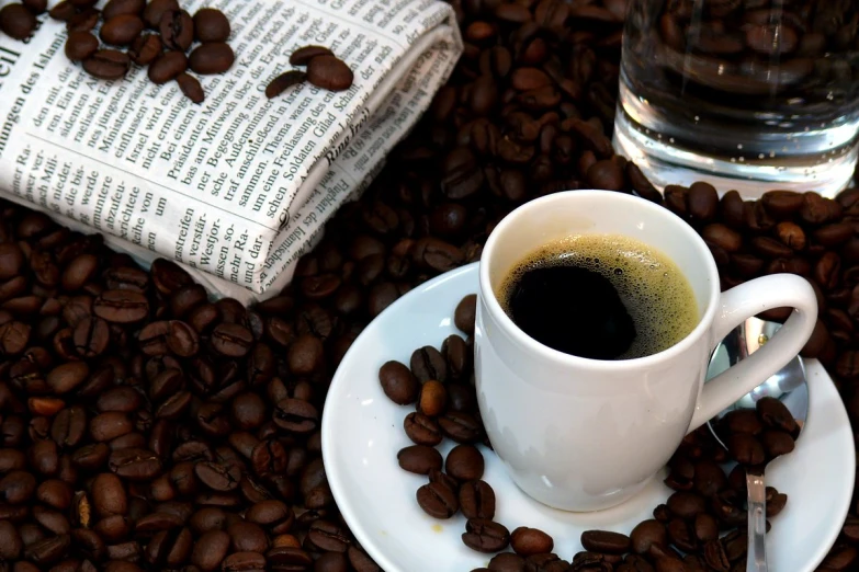 a cup of coffee is sitting next to some coffee beans