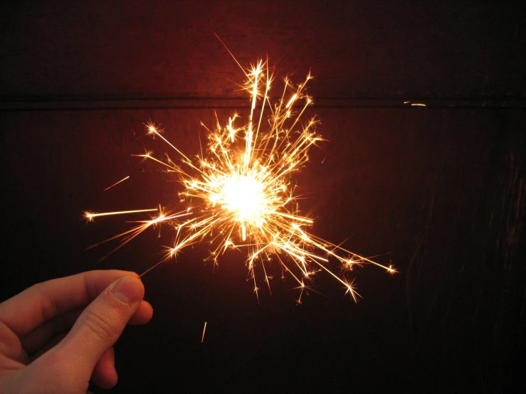 someone holds a small firework in their hand