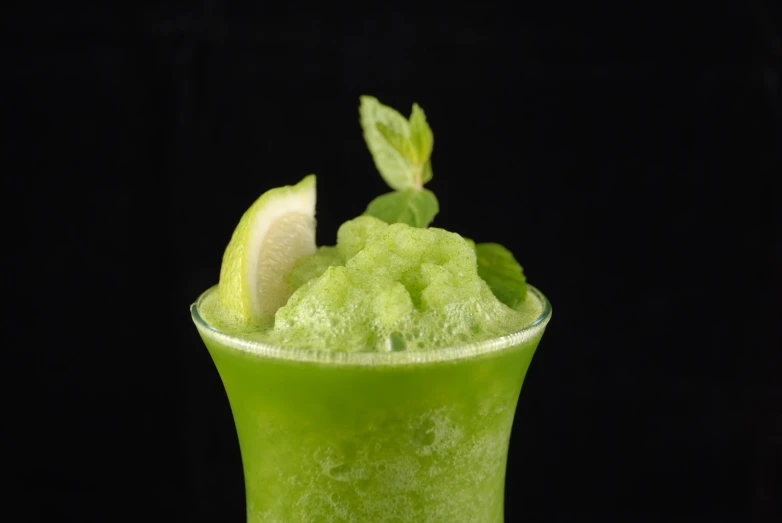 a bright green drink with a lemon slice garnished with fresh mint