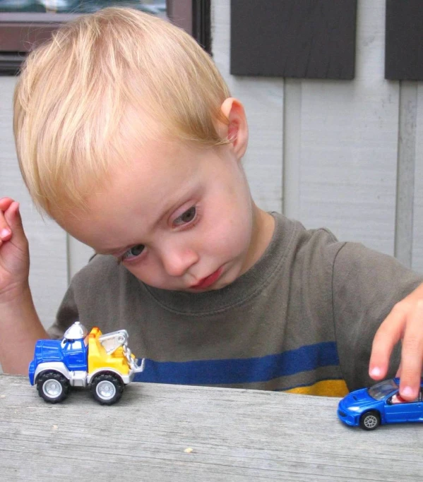 a small boy looking at a toy truck