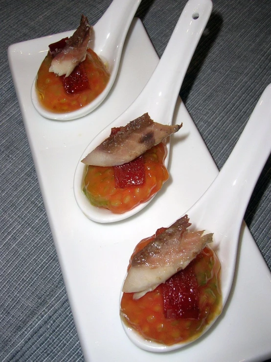 small pieces of prepared food on white spoons