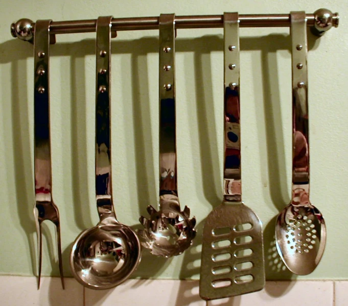 various spoons, spatulas, and pans hang from a wall